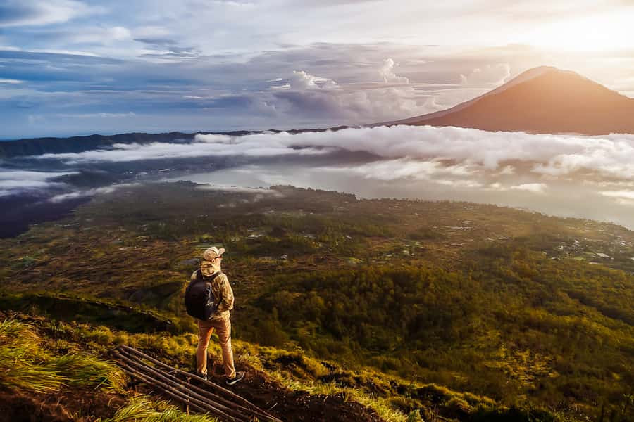 A walker on the rim of Mount Batur as the sun comes up over Lake Batur